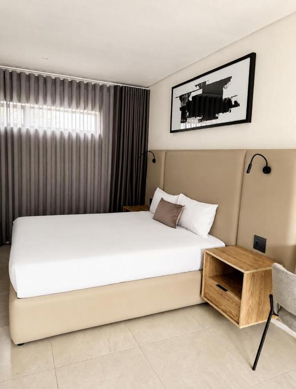 a bedroom with a large white bed and a table at The Spear Guest Lodge in Graskop
