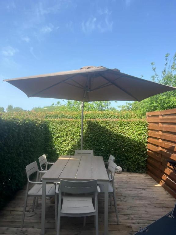 a table and chairs with an umbrella on a patio at Maison à Westende in Middelkerke