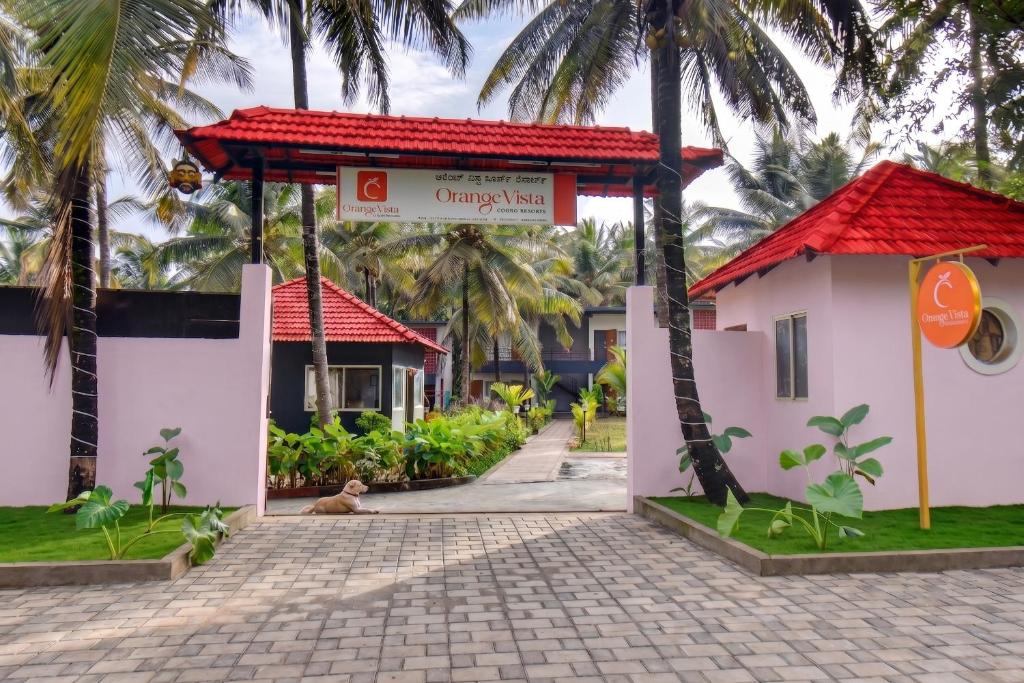a gate to a house with palm trees at Orange Vista Resort Coorg in Kushālnagar