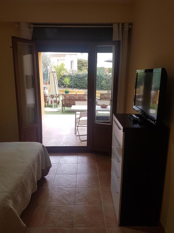 1 dormitorio con 1 cama, TV y patio en Costa Esuri, en Ayamonte