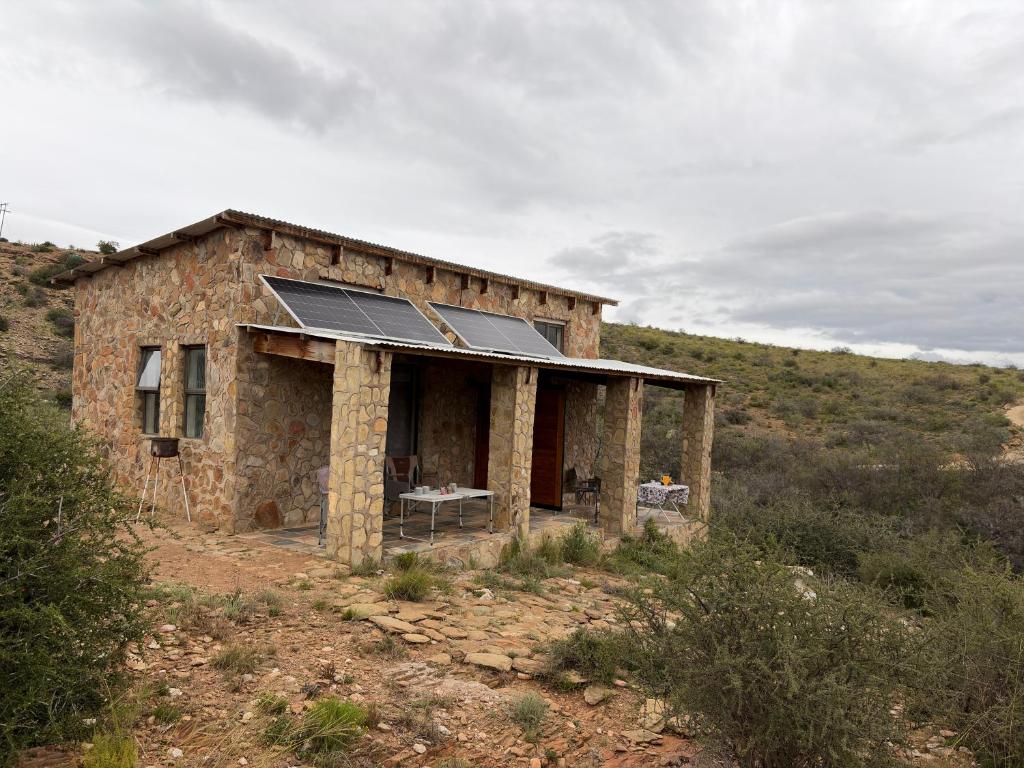 an old stone house with solar panels on it at Shama Lodge - "Silent Sunsets" Duplex Cottage in Steytlerville