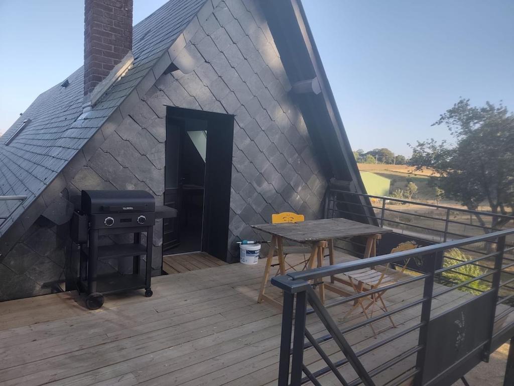 a patio with a grill and a table on a deck at Logement à la ferme in Bréauté
