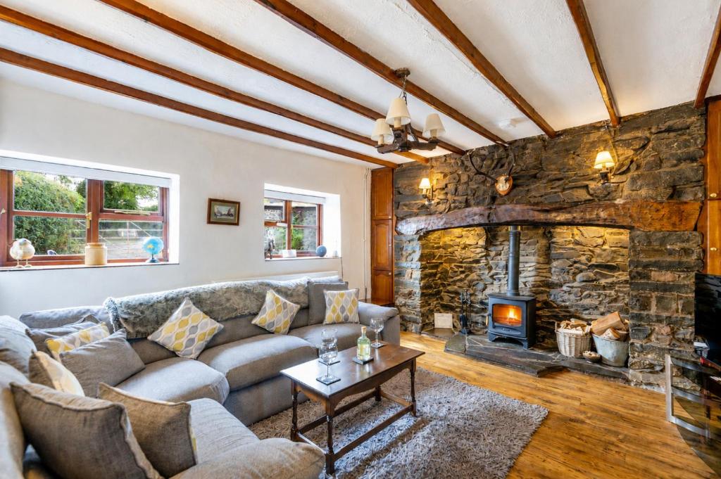 a living room with a large stone fireplace at Garth Cottage in Gwaynynog