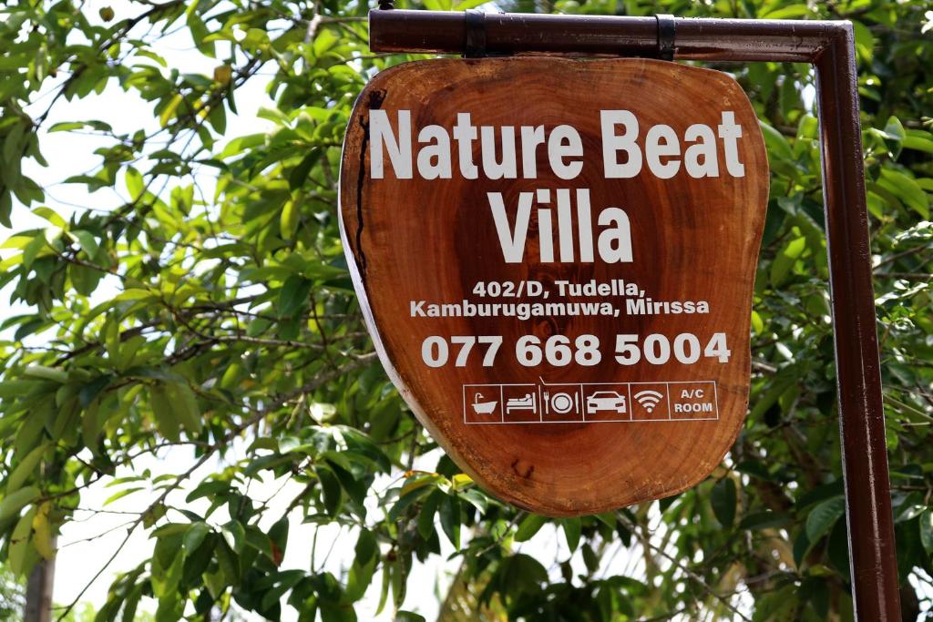 a sign for a nature beat villa on a tree at Nature Beat villa in Mirissa
