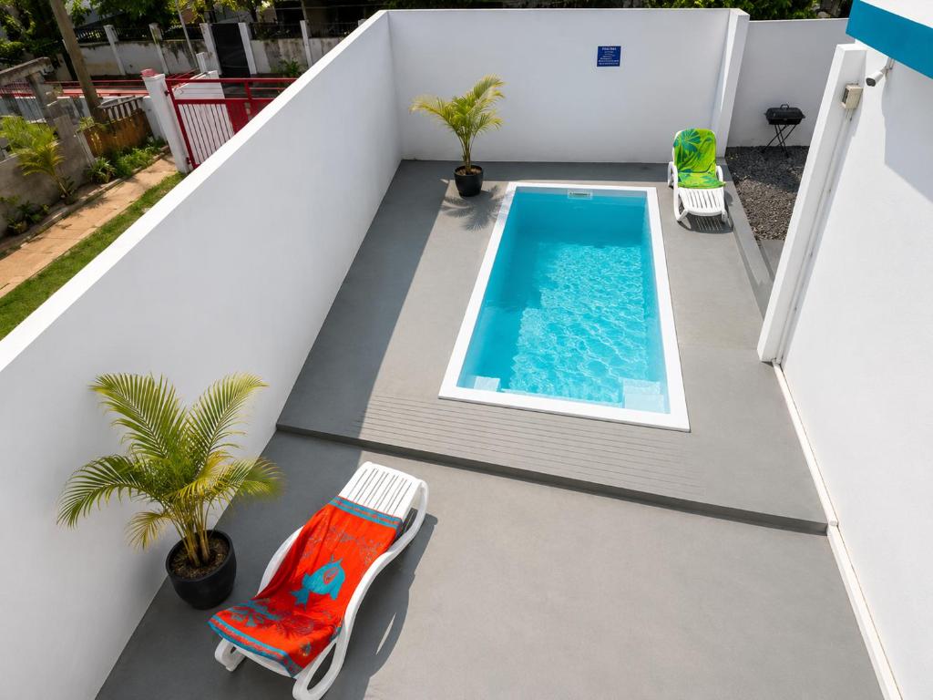 a view of a swimming pool on a balcony with a chair at Superbe Villa 6 personnes avec piscine - Le Sega in Pointe aux Sable