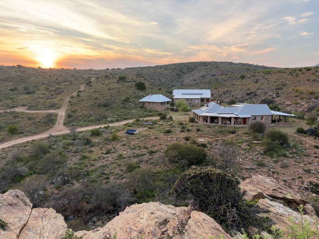a house on top of a hill with the sunset in the background at Shama Private Group Lodge in Steytlerville