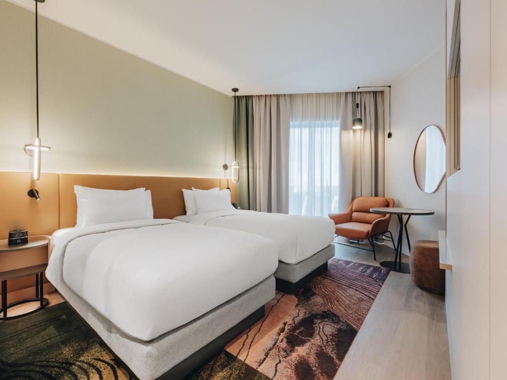 a hotel room with a large white bed and a chair at Hyatt Place Tallinn in Tallinn