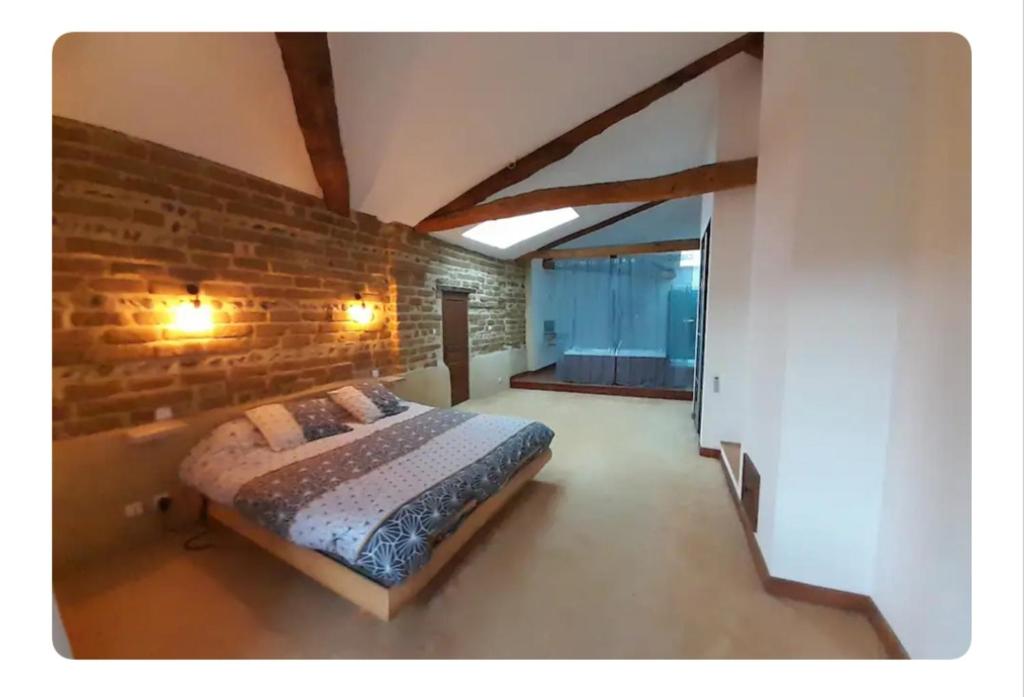 a bedroom with a bed in a brick wall at Chambres d'hôtes le Brensole in Brens
