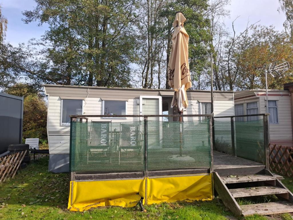 a view of a caravan with a fence and an umbrella at Mobilheim Lipno in Černá v Pošumaví