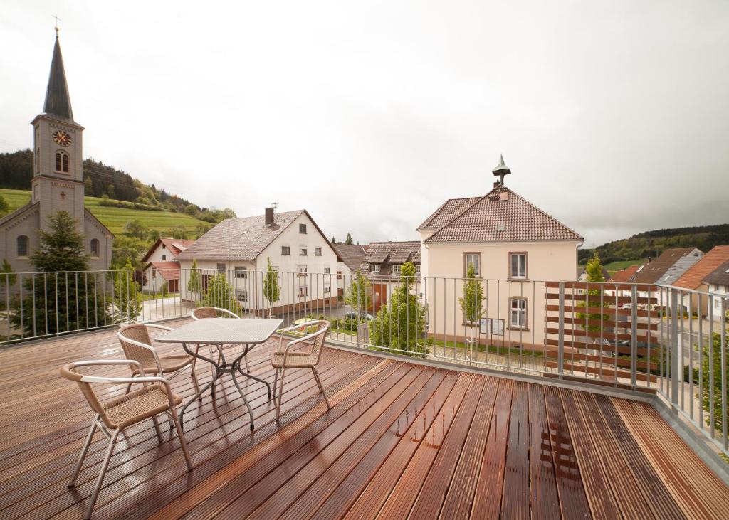 a balcony with a table and chairs on a wooden deck at Schwarzwald Apartments Fürstenberg in Hüfingen
