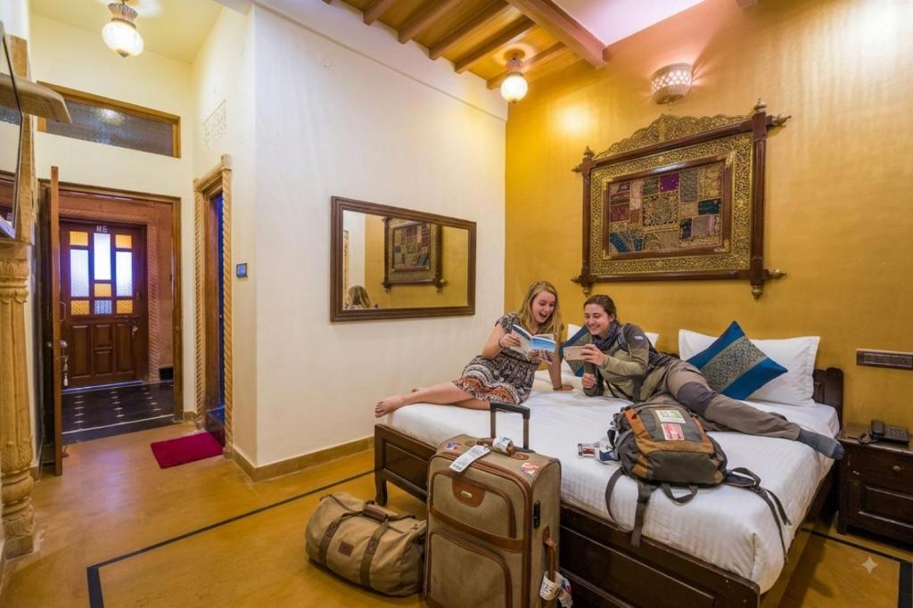 two women sitting on a bed in a room with luggage at Hotel Toffu safari in Jaisalmer