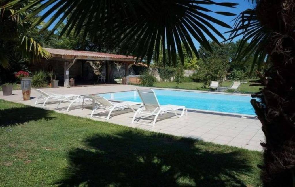 two lounge chairs and a swimming pool in a yard at Domaine des Chais in Thénac