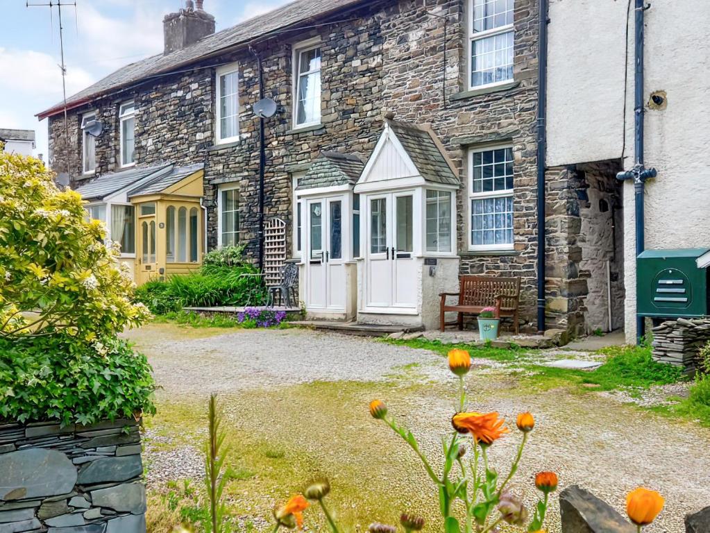 a stone house with a white door and flowers in front at 1 Tower Cottage in Portinscale