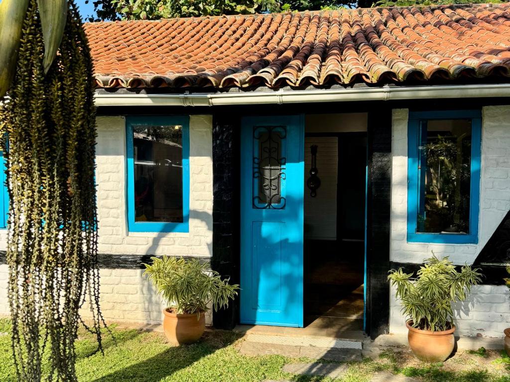 a house with a blue door and potted plants at Peixe Crew Manguinhos in Búzios