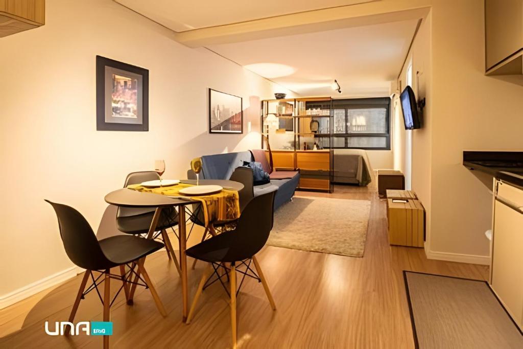 a living room with a table and chairs and a couch at Studio 907 Flow Live - Parque Una + garagem in Pelotas