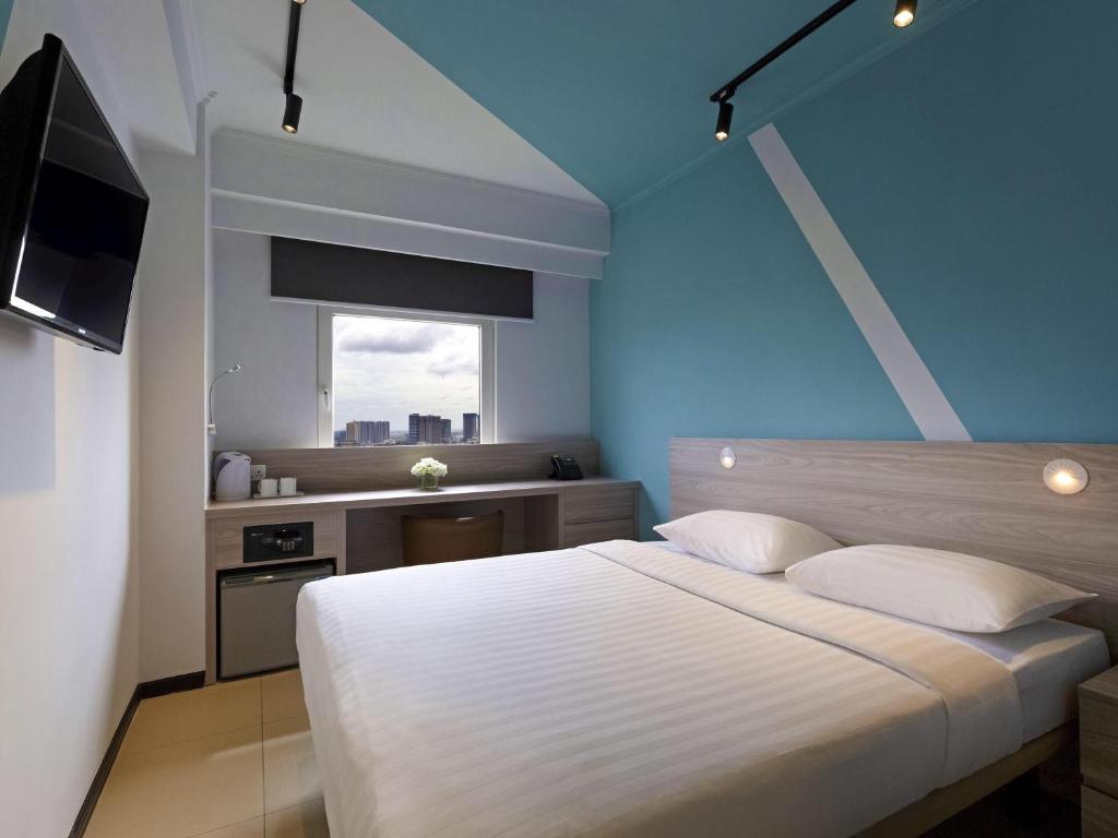 a bedroom with a large white bed and a window at ibis budget Phnom Penh Riverside in Phnom Penh