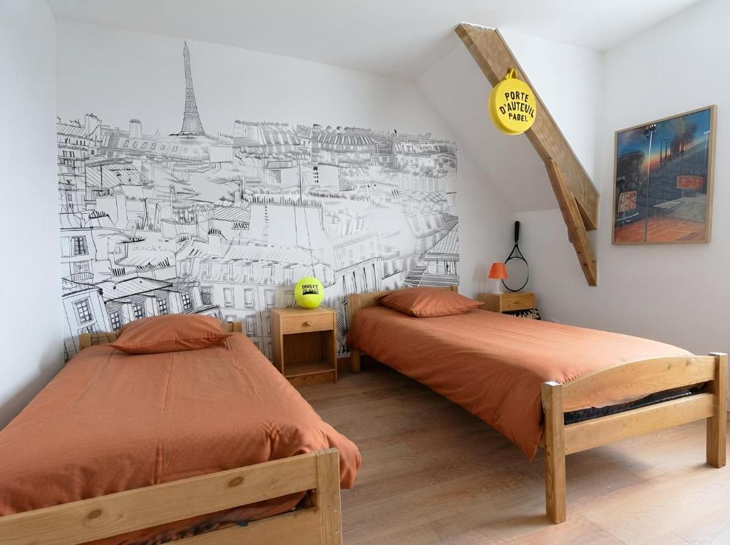 a bedroom with two beds and a mural of a city at Le tie-break in Pont-Croix