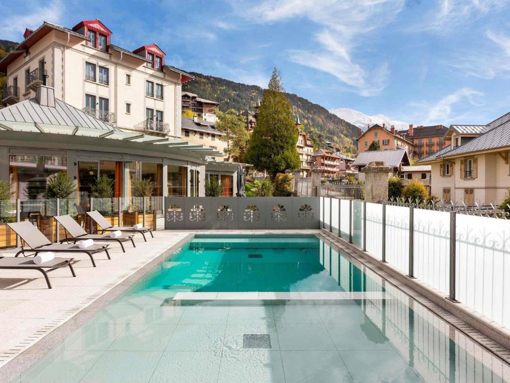 a swimming pool with chairs next to a building at Le Saint Gervais Hotel & Spa Handwritten Collection in Saint-Gervais-les-Bains