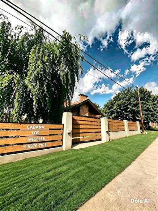 a fence in front of a yard with green grass at Cabaña Los Angeles in Villa General Belgrano