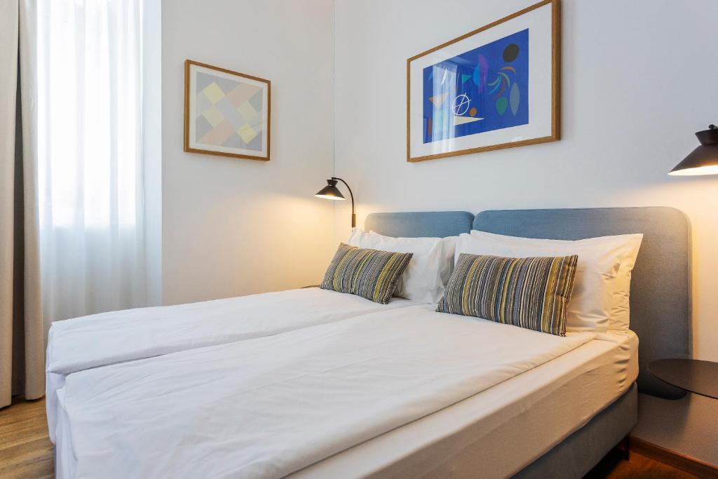 a bed with white sheets and pillows in a room at Villa Rossella in Locarno