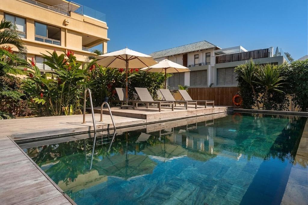 a swimming pool with chairs and umbrellas next to a building at NEW Beachfront 3-bedrooms Apartment in Tamarin, Ocean Legend in Tamarin