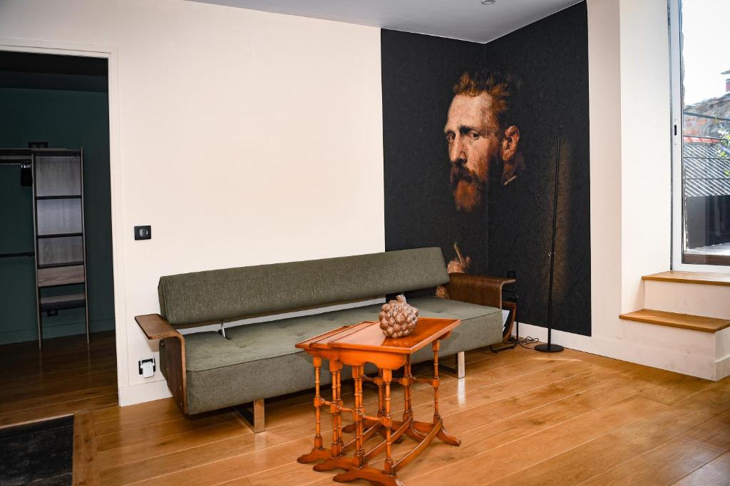 a living room with a couch and a painting on the wall at Les Gens Heureux Appartement GLAZ in Paimpol
