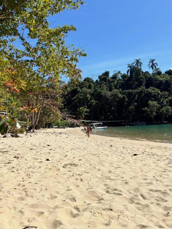 a person walking on a sandy beach near the water at Pousada Casa Hospedaria in Paraty