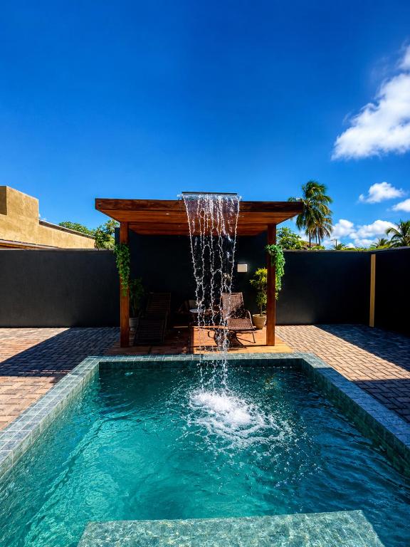 a swimming pool with a fountain on a patio at Casa com vista para o mar e piscina em Milagres in São Miguel dos Milagres