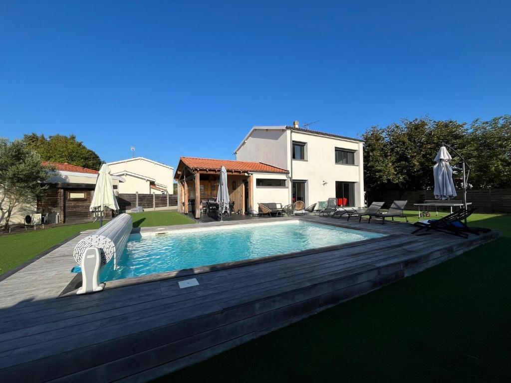a swimming pool with a wooden deck and a house at Villa Palmyra - Piscine Privée in La Teste-de-Buch
