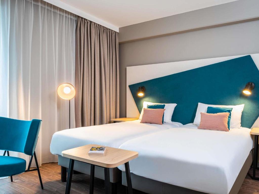 a hotel room with a large bed and a table at Aparthotel Adagio Heidelberg in Heidelberg