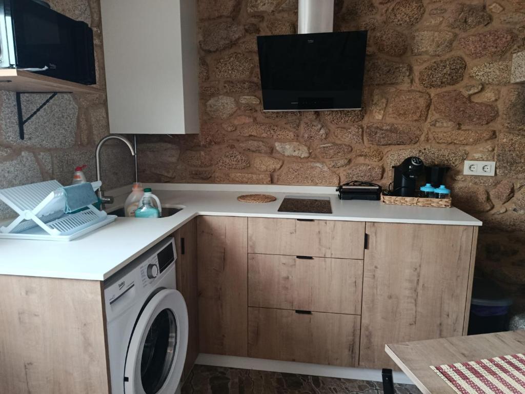 a kitchen with a washing machine and a tv on the wall at A casa do sal 