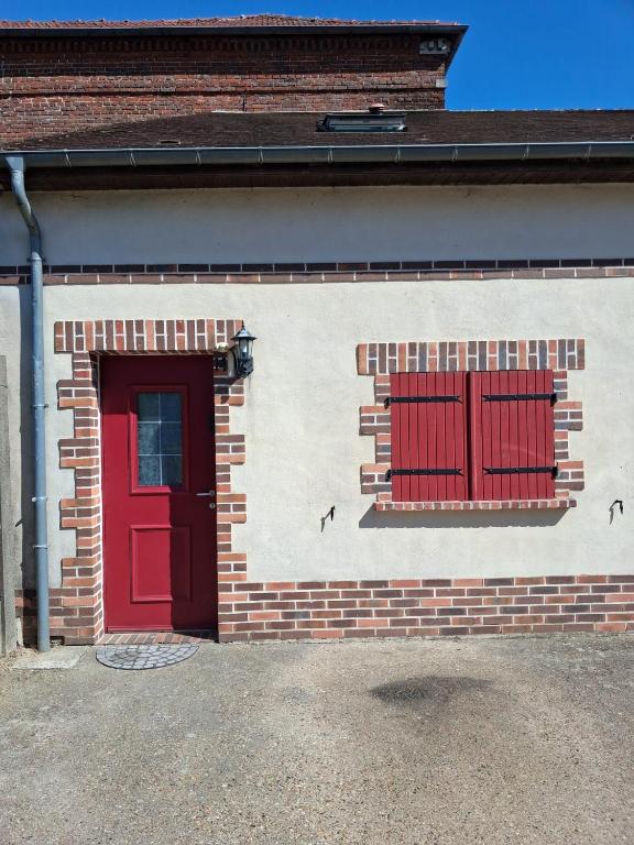 a red door and windows on a brick building at L'Envol in Tillé