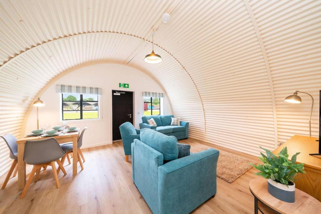 a living room with an arched ceiling and blue chairs at Cultybraggan Hut 35 in Comrie