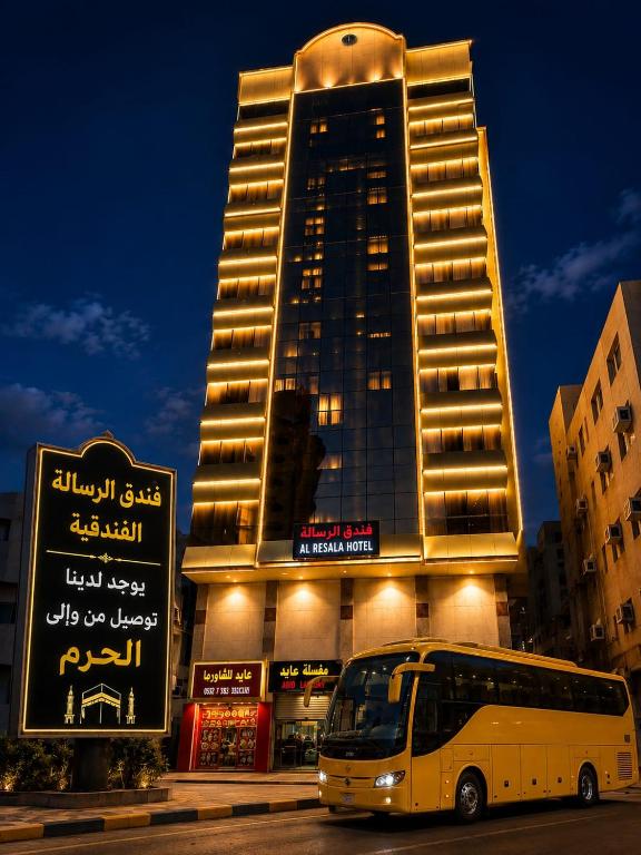 a bus is parked in front of a building at فندق الرسالة الفندقية ذاخر توصيل مجاني من والى الحرم Al-Risala Hotel Zakhar Free delivery to and from the Haram in An Naqāʼ