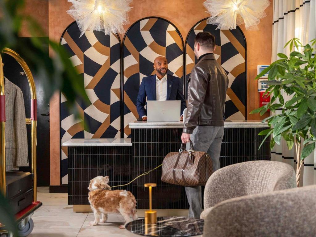 two men standing at a counter with a dog on a leash at Hotel Maison Hamelin Paris - Handwritten Collection in Paris