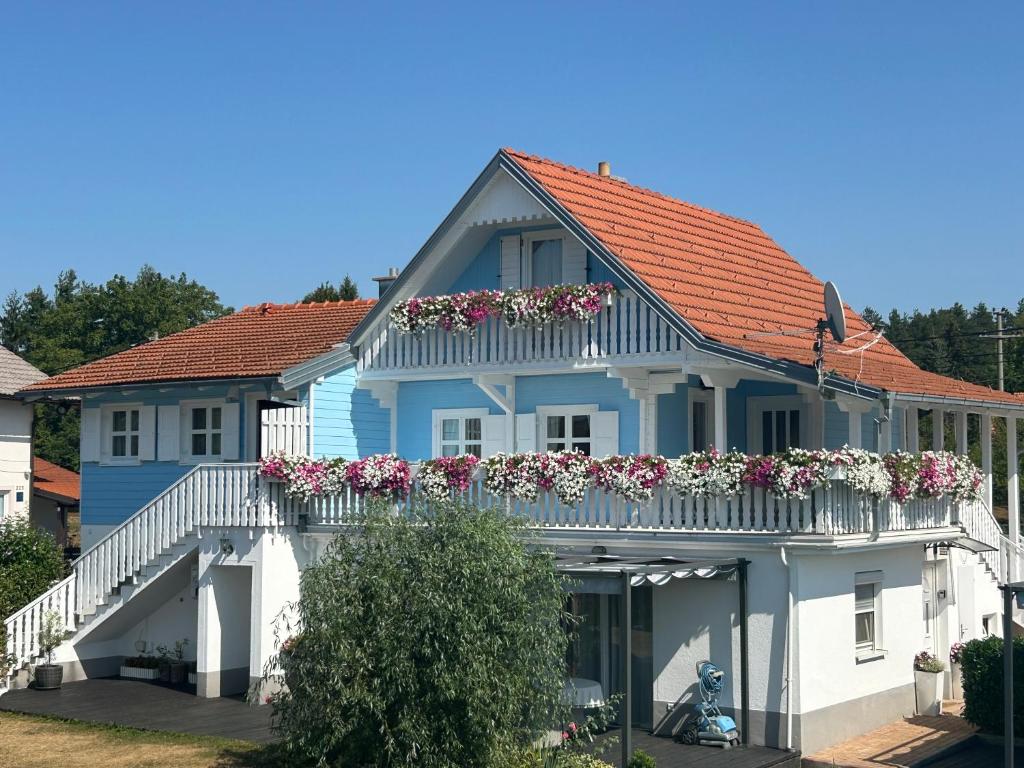 a blue house with flowers on a balcony at Pool Apartments Plitvice Lakes in Grabovac