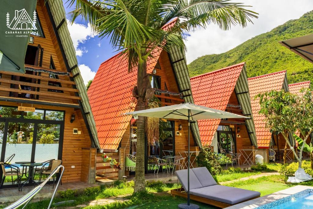 a house with a palm tree and an umbrella at Cabañas Alpinas en Oxapampa in Oxapampa