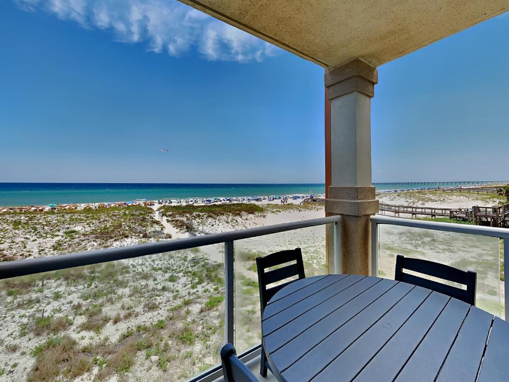 a porch with a table and chairs and the beach at Beach Club #206A in Pensacola Beach