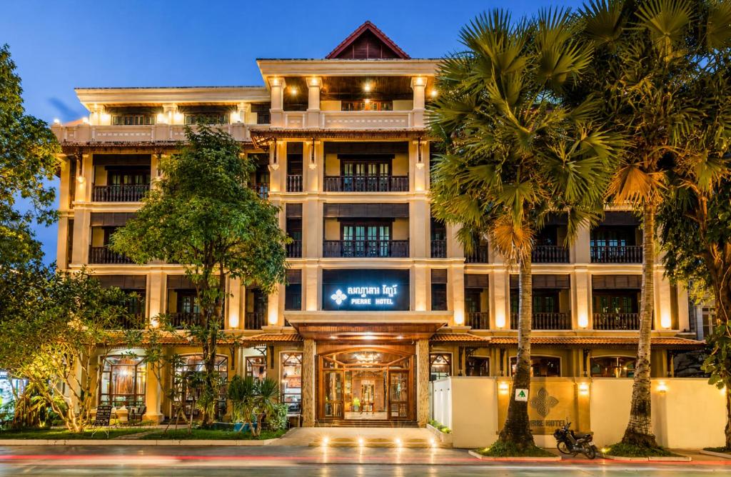 a large building with palm trees in front of it at Pierre Hotel in Siem Reap