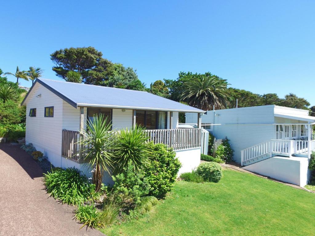 a white house with a porch and a yard at Waiheke Island Motel in Ostend