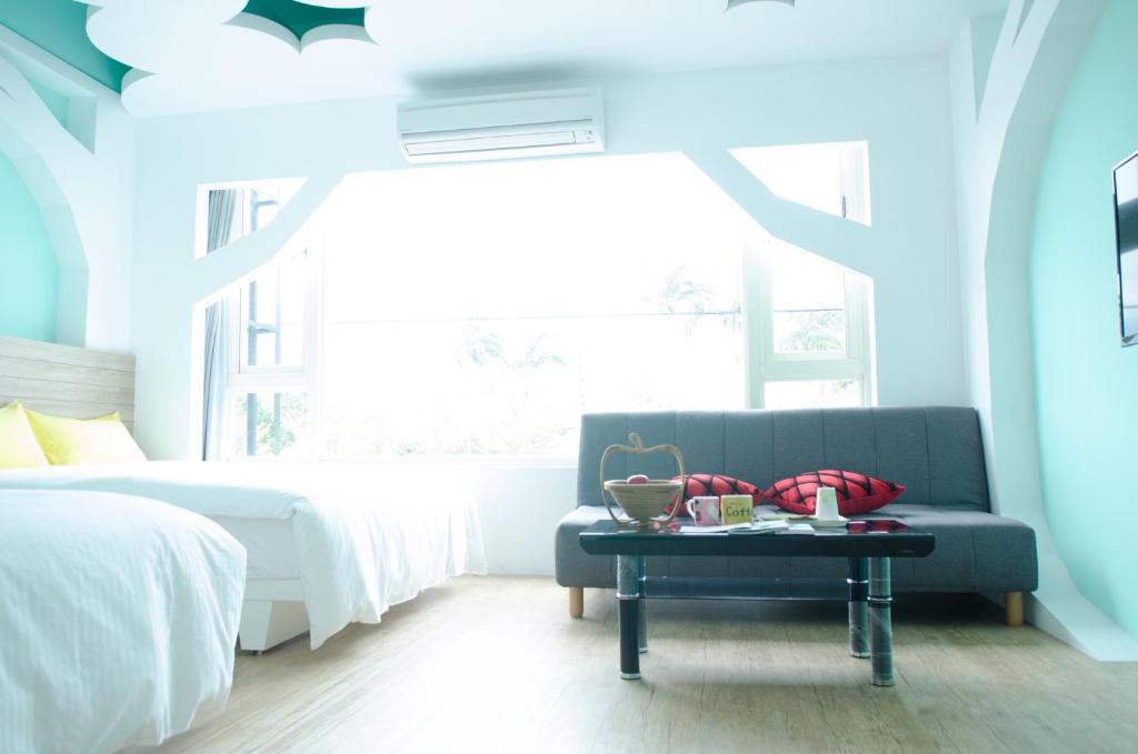 a bedroom with a blue couch and a table at Apple Tree Bed and Breakfast in Hualien City
