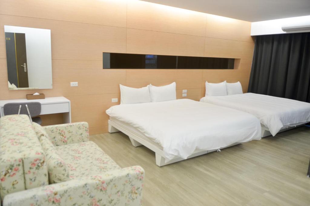 a hotel room with two beds and a couch at Apple Tree Bed and Breakfast in Hualien City