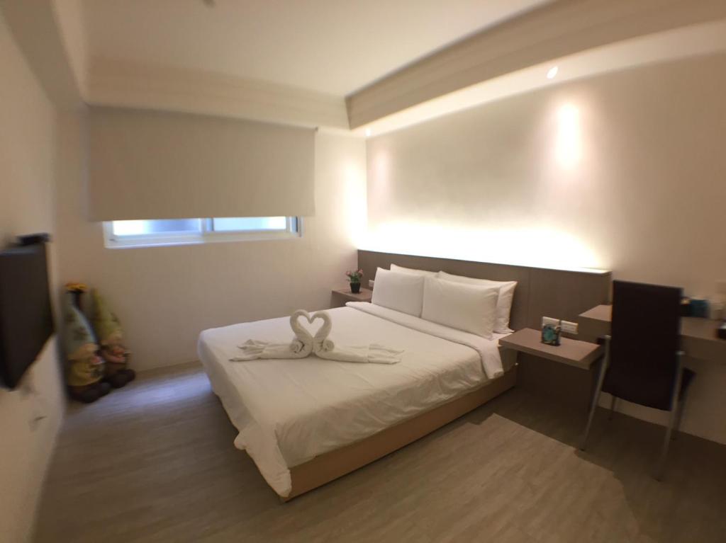 um quarto de hotel com uma cama com uma toalha em Happiness Dot em Tamsui