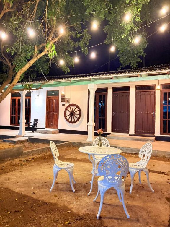 a table and three chairs and a table and a building at The Wild Lotus YALA in Tissamaharama