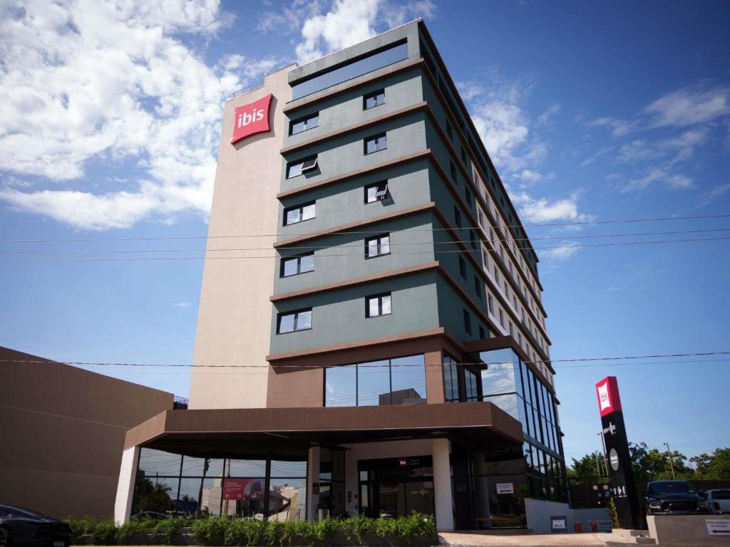 a tall building with a red hotel sign on it at ibis Tangará Da Serra in Tangara da Serra