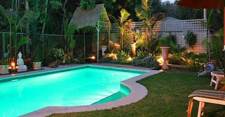 ein Schwimmbad in einem Garten in der Nacht mit Lichtern in der Unterkunft Weeroona Bed And Breakfast in Rye