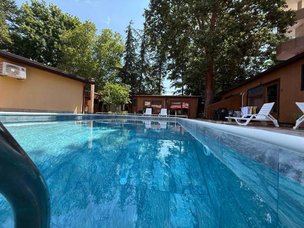 a large blue swimming pool with chairs and a building at Villas Chinara in Kranevo