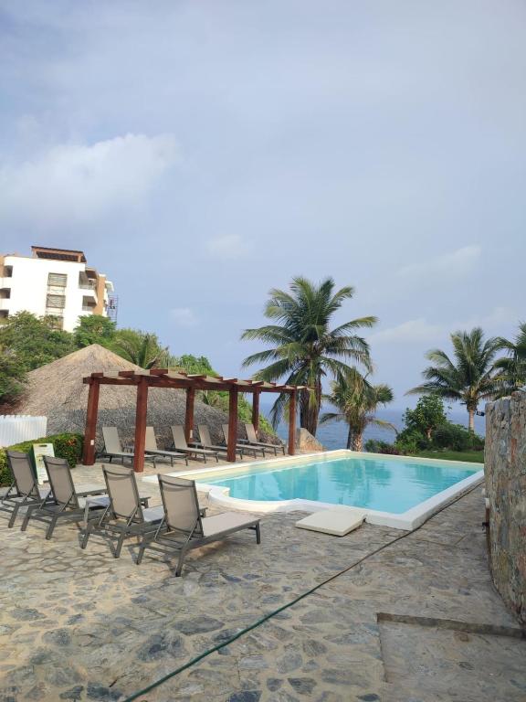 a swimming pool with lounge chairs next to the ocean at Villas & Resort Luz de Luna in Santa Cruz Huatulco