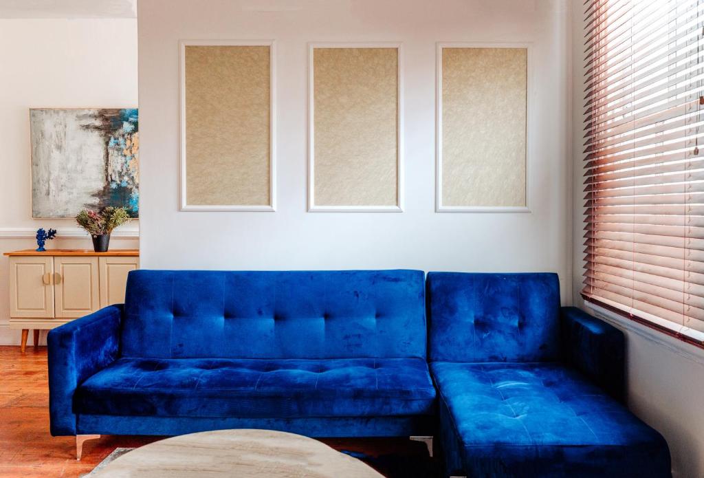 a blue couch sitting in a living room at Sand In My Shoes in Muizenberg