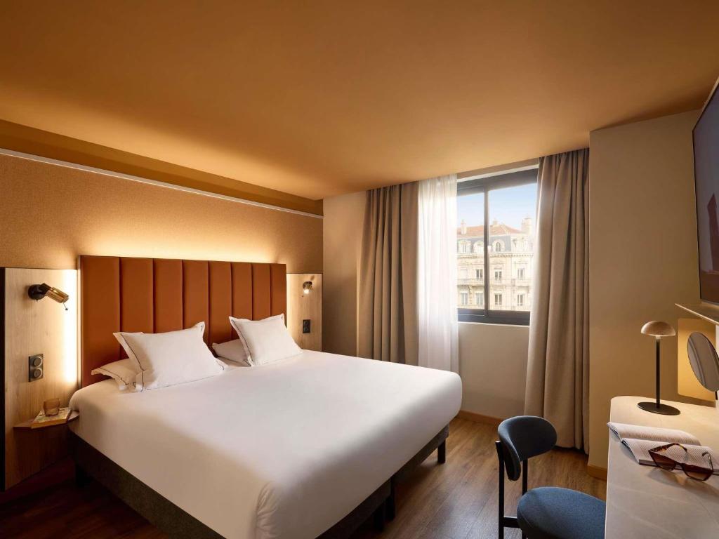 a hotel room with a large bed and a window at You Hotel de France Valence - Handwritten Collection in Valence